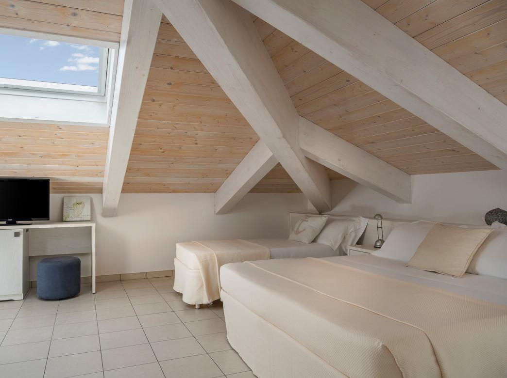 Camera da letto in mansarda con travi a vista e arredamento minimalista.