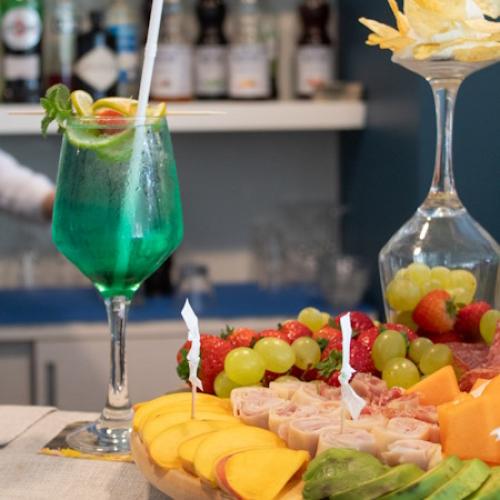 Cocktail blu con frutta fresca e stuzzichini su un tavolo elegante.