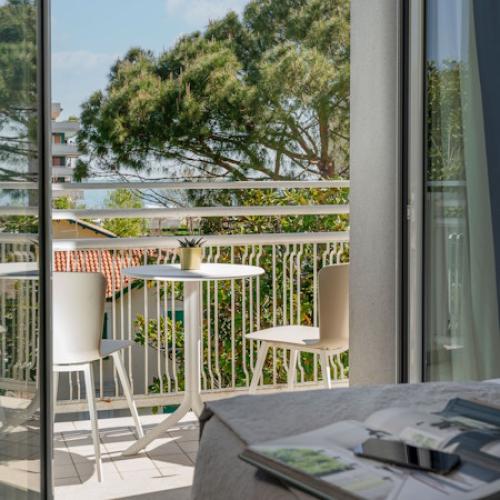 Balcone con tavolo e sedie, vista su alberi e cielo sereno.