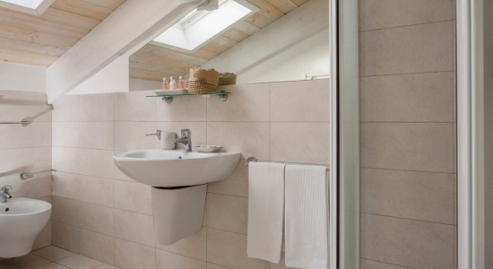 Bagno moderno con soffitto in legno e luce naturale da lucernari.